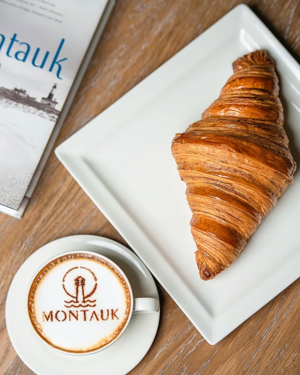 A croissant and a Montauk coffee on a bakery table