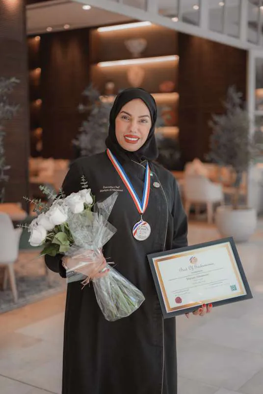 Chef Mariam with her medal and flowers in the cafe
