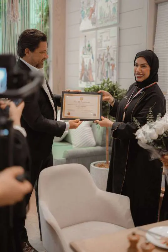 A certificate presented to Chef Mariam at a garden ceremony