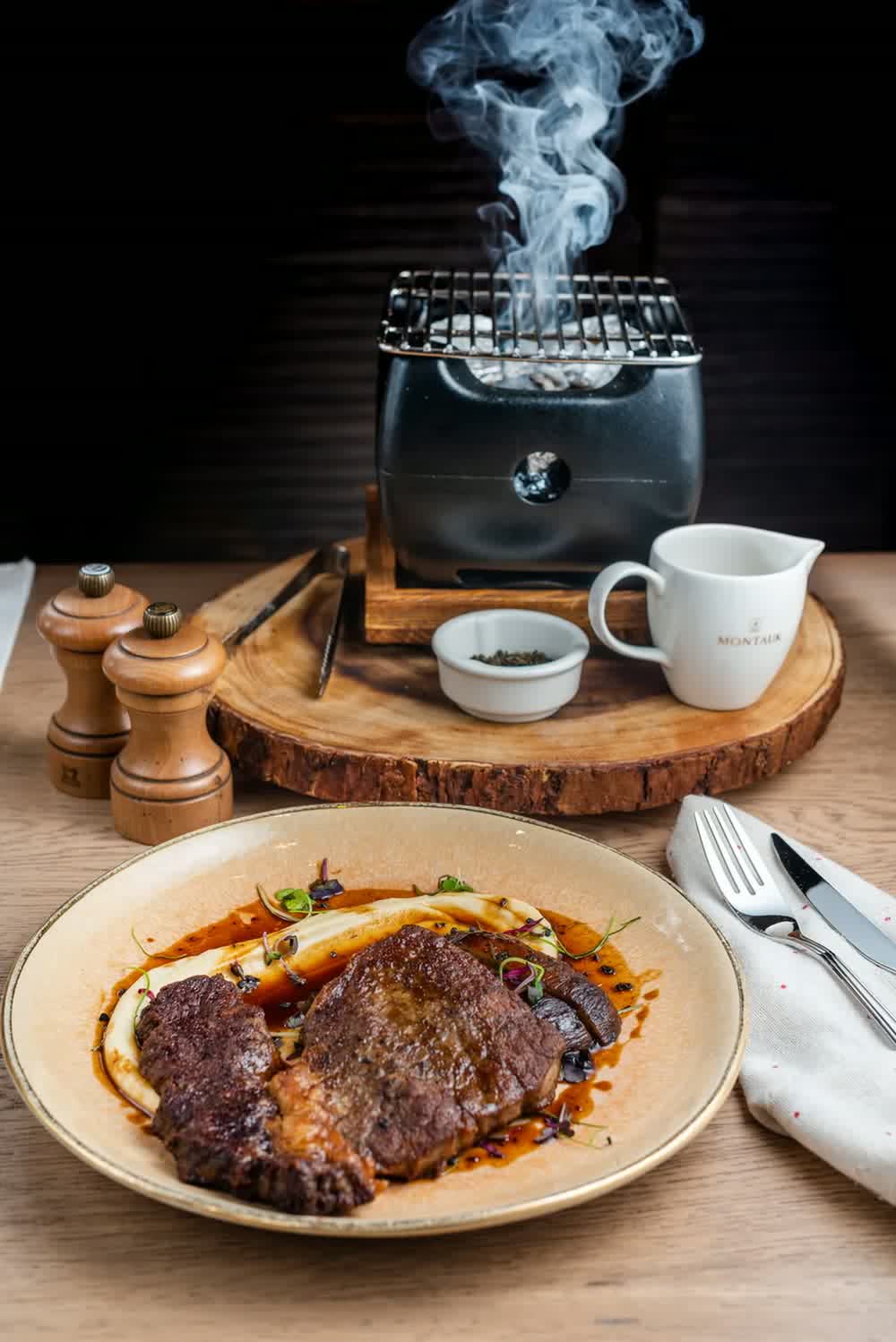 An MTK Smoke House steak under a smoking cloche